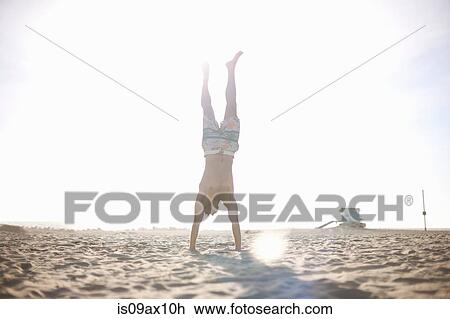 Mid adult man doing handstand on beach View Large Photo Image Stock Image - Mid adult man doing handstand on beach. Fotosearch