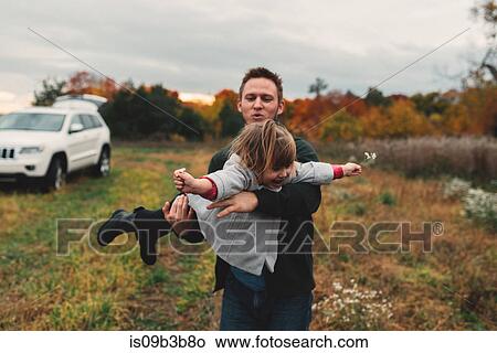 Picture - Mid adult man playing with toddler daughter in field. Fotosearch