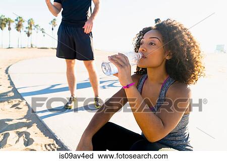 Mid adult woman, by beach, drinking from water bottle View Large Photo Image Stock Image - Mid adult woman, by beach, drinking from water bottle. Fotosearch