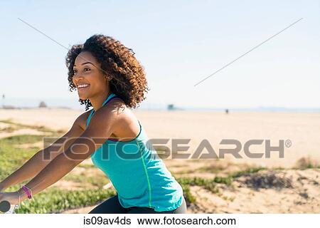 Stock Photograph - Mid adult woman cycling near beach. Fotosearch