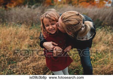Mid adult woman kissing daughter on cheek in field View Large Photo Image Stock Photography - Mid adult woman kissing daughter on cheek in field. Fotosearch
