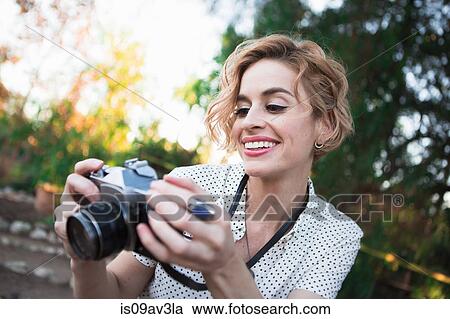 Mid adult woman looking at back of camera, outdoors, smiling View Large Photo Image Stock Image - Mid adult woman looking at back of camera, outdoors, smiling. Fotosearch