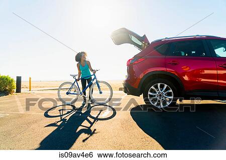Mid adult woman putting bicycle into car boot View Large Photo Image Stock Photograph - Mid adult woman putting bicycle into car boot. Fotosearch