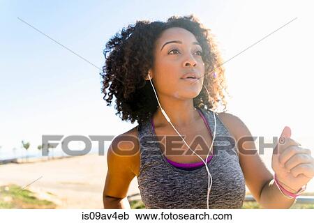 Mid adult woman running by beach, wearing earphones View Large Photo Image Stock Image - Mid adult woman running by beach, wearing earphones. Fotosearch