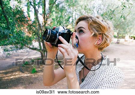 Mid adult woman taking photographs in park View Large Photo Image Stock Image - Mid adult woman taking photographs in park. Fotosearch
