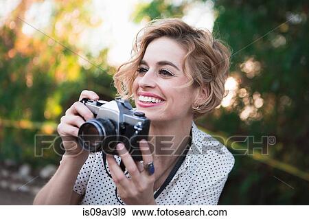 Mid adult woman taking photographs, outdoors, smiling View Large Photo Image Stock Photo - Mid adult woman taking photographs, outdoors, smiling. Fotosearch