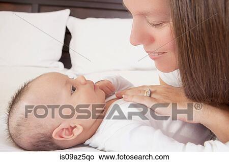 Mother admiring baby boy lying on bed View Large Photo Image Picture - Mother admiring baby boy lying on bed. Fotosearch