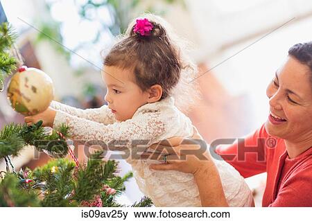Stock Photo - Mother and daughter decorating Christmas tree. Fotosearch