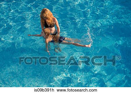 Stock Image - Mother and daughter in swimming pool, mother teacher daughter to swim. Fotosearch