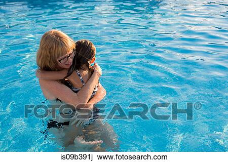 Stock Image - Mother and daughter in swimming pool, hugging. Fotosearch