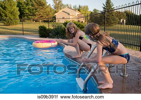 Stock Image - Mother and daughter on edge of swimming pool, ready to dive in. Fotosearch