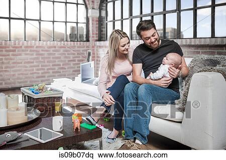 Mother and father sitting on sofa with baby girl View Large Photo Image Stock Photography - Mother and father sitting on sofa with baby girl. Fotosearch