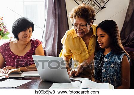 Stock Photo - Mother and grandmother helping girl with homework using laptop. Fotosearch