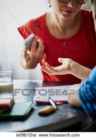 Stock Photograph - Mother and son at dining table having discussion. Fotosearch