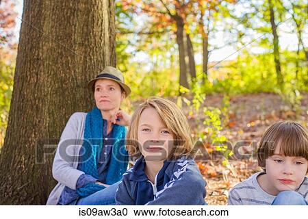 Stock Image - Mother and sons, sitting in forest. Fotosearch