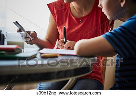 Stock Photography - Mother at dining table helping son with homework. Fotosearch
