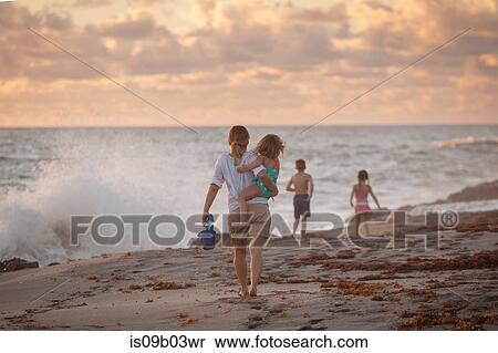 Mother carrying daughter on beach at sunrise, Blowing Rocks Preserve, Jupiter Island, Florida, USA View Large Photo Image Stock Photography - Mother carrying daughter on beach at sunrise, Blowing Rocks Preserve, Jupiter Island, Florida, USA. Fotosearch