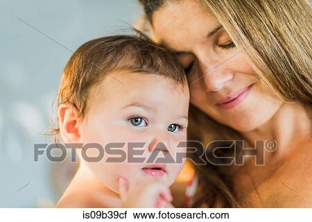 Stock Image - Mother closing eyes, cuddling toddler. Fotosearch