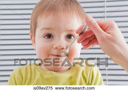 Mother feeding son at home View Large Photo Image Stock Photography - Mother feeding son at home. Fotosearch