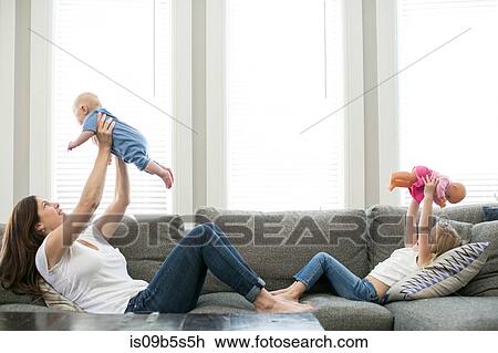 Mother holding baby boy in air across from daughter holding doll in air View Large Photo Image Stock Image - Mother holding baby boy in air across from daughter holding doll in air. Fotosearch