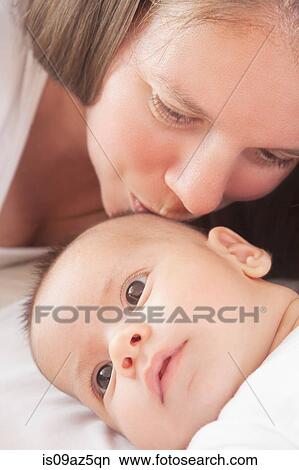 Picture - Mother kissing baby boy on forehead. Fotosearch