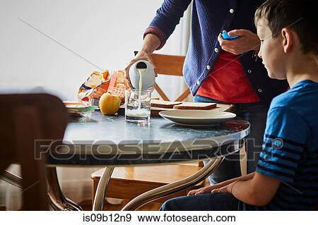 Mother pouring glass of milk for son View Large Photo Image Stock Photo - Mother pouring glass of milk for son. Fotosearch