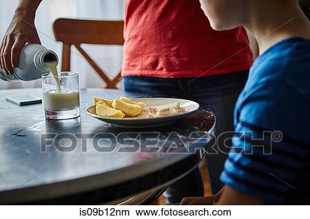 Mother pouring milk for son View Large Photo Image Picture - Mother pouring milk for son. Fotosearch