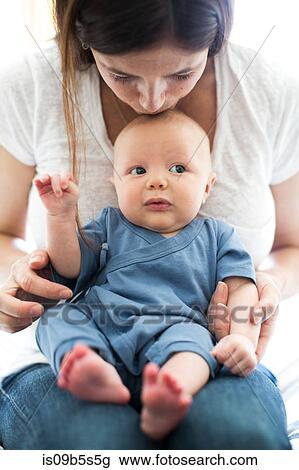 Mother sitting with baby boy on lap, kissing him on head View Large Photo Image Stock Image - Mother sitting with baby boy on lap, kissing him on head. Fotosearch