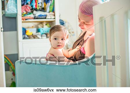 Mother sitting with baby son on nursery sofa View Large Photo Image Stock Photo - Mother sitting with baby son on nursery sofa. Fotosearch
