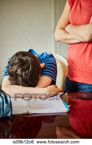 Mother standing by upset son doing homework View Large Photo Image Stock Photograph - Mother standing by upset son doing homework. Fotosearch
