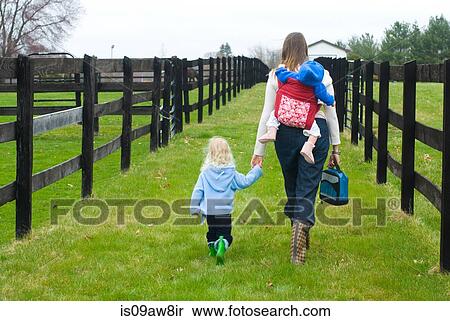 Mother walking in field with young daughter, carrying baby girl on back, rear view View Large Photo Image Stock Photography - Mother walking in field with young daughter, carrying baby girl on back, rear view. Fotosearch
