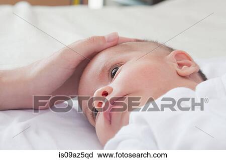 Stock Image - Mothers hand stroking baby boys head. Fotosearch