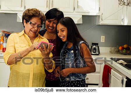Multi generation family looking at smartphone smiling View Large Photo Image Stock Photo - Multi generation family looking at smartphone smiling. Fotosearch