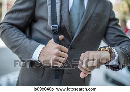 Neck down view of businessman checking wristwatch in city View Large Photo Image Stock Photography - Neck down view of businessman checking wristwatch in city. Fotosearch