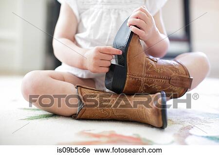 Neck down view of female toddler sitting on floor wearing cowboy boots View Large Photo Image Stock Image - Neck down view of female toddler sitting on floor wearing cowboy boots. Fotosearch