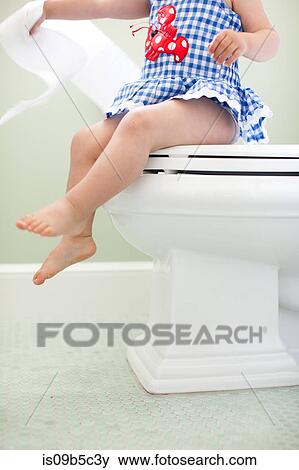 Neck down view of female toddler sitting on toilet seat pulling toilet paper View Large Photo Image Stock Photo - Neck down view of female toddler sitting on toilet seat pulling toilet paper. Fotosearch