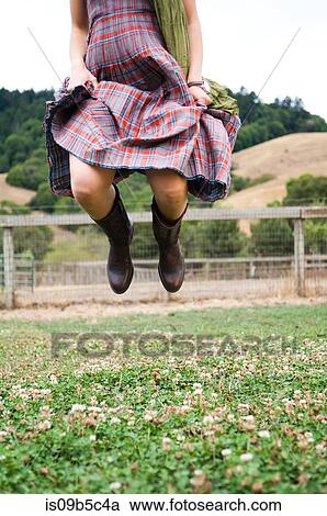 Neck down view of woman in checkered dress jumping mid air in field View Large Photo Image Stock Image - Neck down view of woman in checkered dress jumping mid air in field. Fotosearch