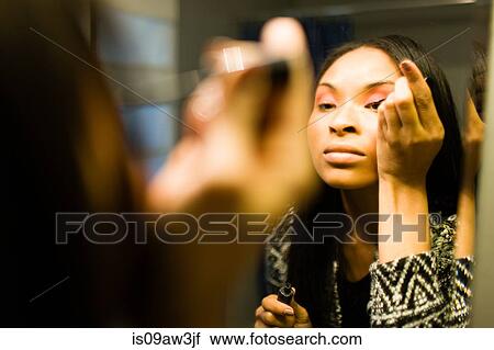 Over shoulder mirror image of young woman putting on eye shadow in bathroom View Large Photo Image Stock Image - Over shoulder mirror image of young woman putting on eye shadow in bathroom. Fotosearch