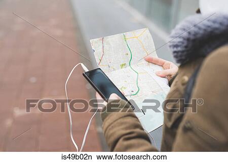 Over shoulder view of female backpacker with smartphone looking at map on city sidewalk View Large Photo Image Picture - Over shoulder view of female backpacker with smartphone looking at map on city sidewalk. Fotosearch