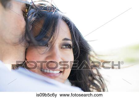Stock Photo - Over shoulder view of man kissing girlfriend on cheek. Fotosearch