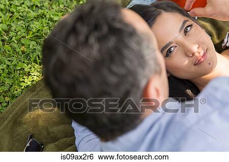 Over shoulder view of young woman lying on grass View Large Photo Image Stock Photograph - Over shoulder view of young woman lying on grass. Fotosearch