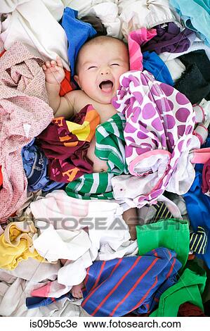 Stock Image - Overhead portrait of baby girl lying in laundry. Fotosearch