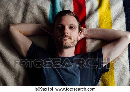 Overhead portrait of confident man lying on striped blanket with hands behind head View Large Photo Image Stock Image - Overhead portrait of confident man lying on striped blanket with hands behind head. Fotosearch