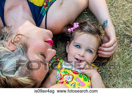 Overhead portrait of mid adult woman and blue eyed toddler daughter lying on grass View Large Photo Image Stock Image - Overhead portrait of mid adult woman and blue eyed toddler daughter lying on grass. Fotosearch