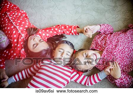 Overhead view of children wearing pyjamas lying on carpet holding hands eyes closed View Large Photo Image Stock Image - Overhead view of children wearing pyjamas lying on carpet holding hands eyes closed. Fotosearch