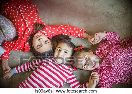Overhead view of children wearing pyjamas lying on carpet looking at camera smiling View Large Photo Image Stock Image - Overhead view of children wearing pyjamas lying on carpet looking at camera smiling. Fotosearch