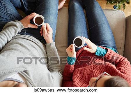 Stock Photograph - Overhead view of couple sitting on sofa holding coffee cup. Fotosearch