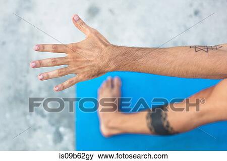 Overhead view of man practicing yoga, standing on yoga mat with arm outstretched View Large Photo Image Stock Photo - Overhead view of man practicing yoga, standing on yoga mat with arm outstretched. Fotosearch