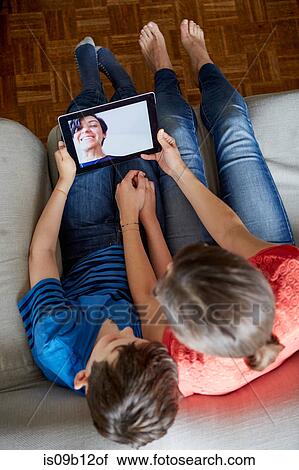 Overhead view of mother and son on sofa using digital tablet View Large Photo Image Stock Image - Overhead view of mother and son on sofa using digital tablet. Fotosearch