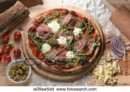 Stock Image - Overhead view of parma ham pizza with green olives. Fotosearch